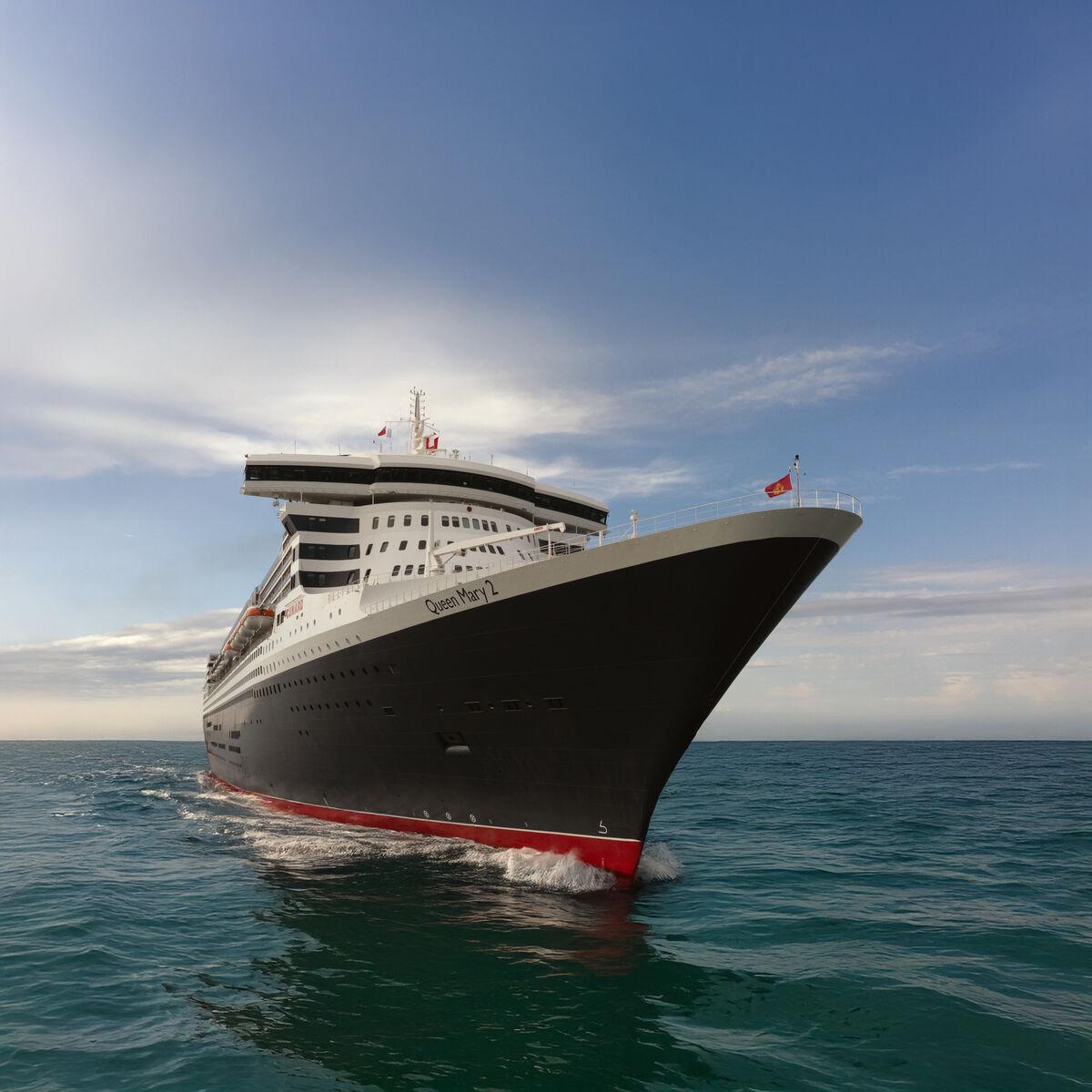 The Queen Mary 2 with her black hull and red waterline on the open sea, seen from the bow